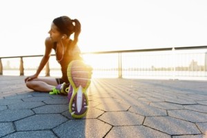 Young female jogger doing stretching exercise at sunrise